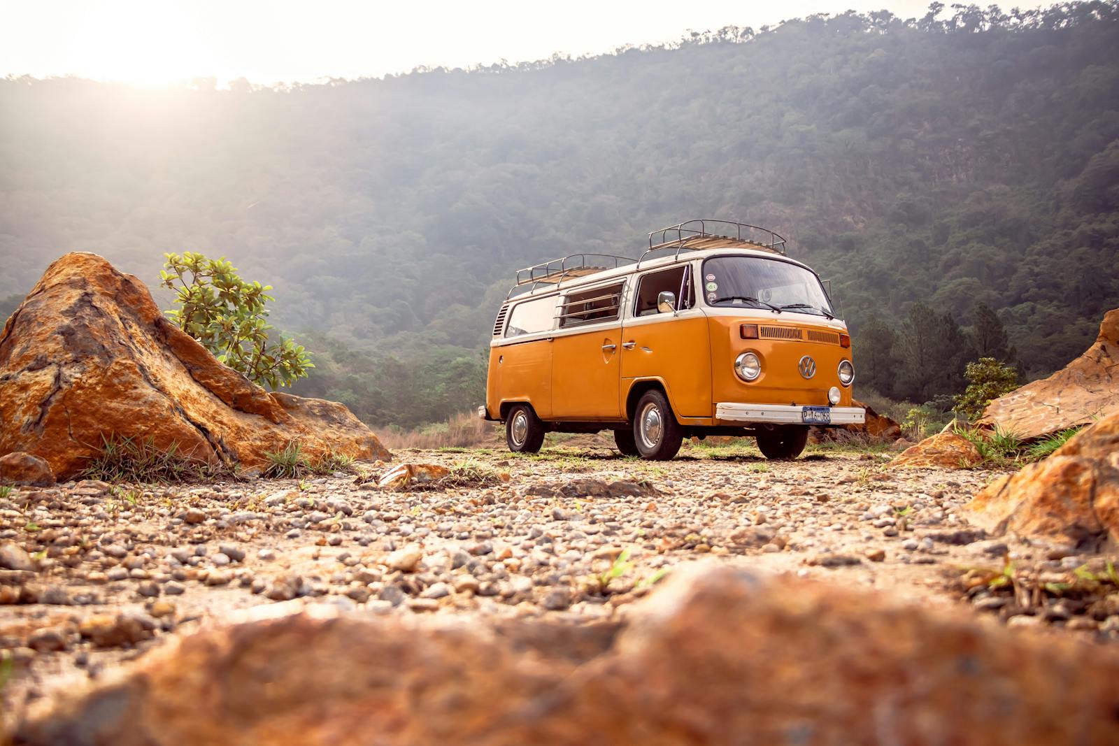 Classic VW van parked on rocky terrain with mountains in Alegría, El Salvador.